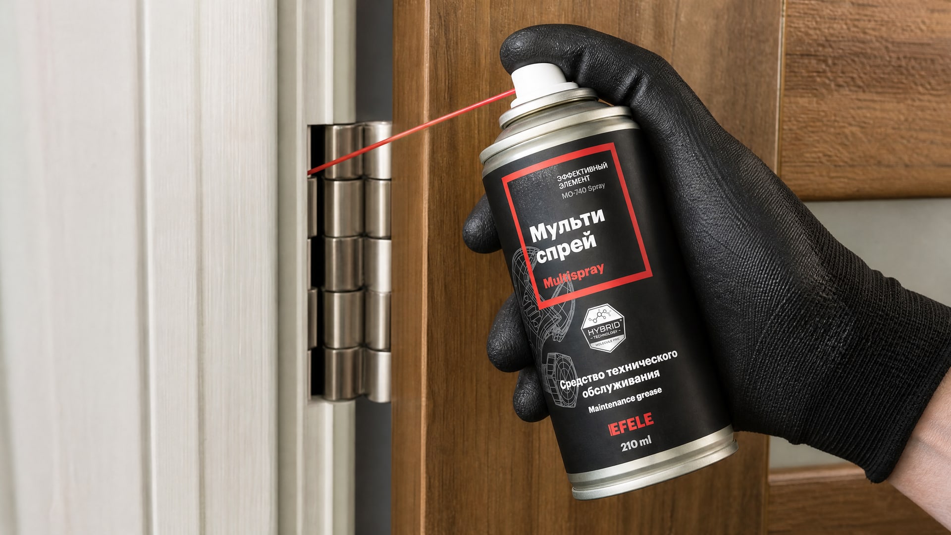 Рука в перчатке смазывает дверные петли мультиспреем EFELE MO-740 Spray.