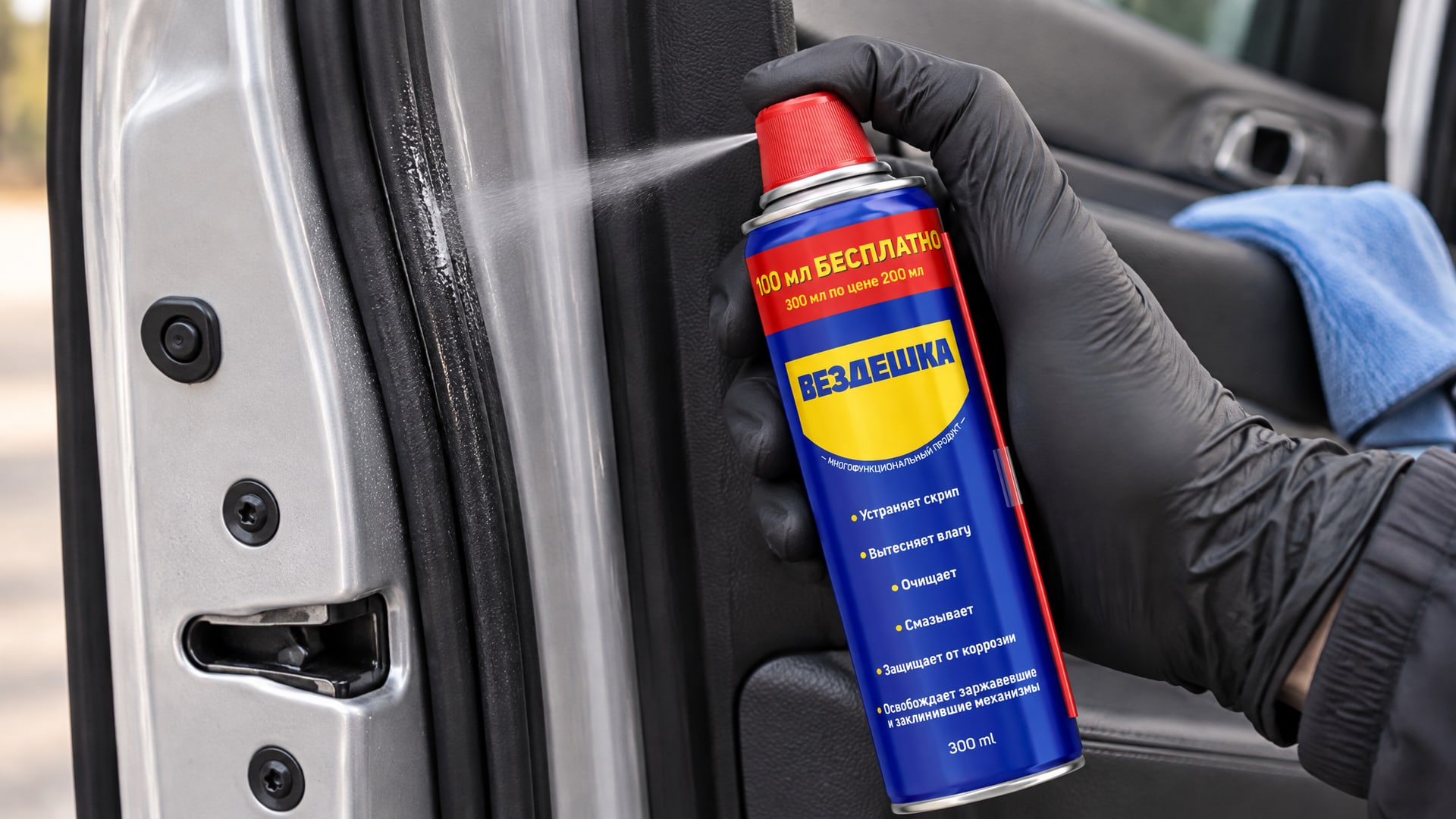 Рука в перчатке наносит универсальную смазку WD-40 на уплотнители двери автомобиля.